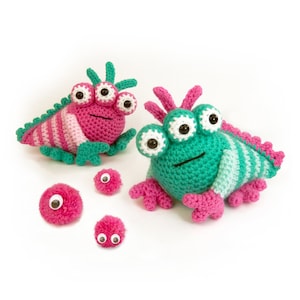 May include: Two crocheted three-eyed monsters, one pink and one green, with pink and white striped bodies.  There are four extra pink pom-poms with black eyes.