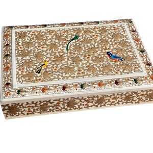 May include: A rectangular box with a white base featuring an intricate pattern of brown leaves and small orange berries. The lid displays three colourful birds in yellow, green, and blue. The sides and top border are decorated with matching leaf motifs.