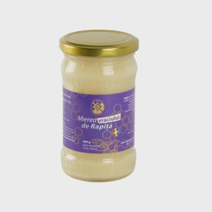Puede incluir: Un tarro de cristal de miel con tapa dorada y etiqueta morada. La etiqueta presenta texto en rumano, una ilustración de abeja y el texto "Mierea Vracului de Rapiță". El tarro contiene 400 g de miel.