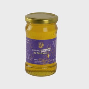 Puede incluir: Un tarro de miel con tapa dorada y etiqueta morada. La etiqueta presenta texto en rumano, incluyendo "Mierea Vracului de Salcâm" y "400 g". La miel en su interior es de color amarillo dorado.