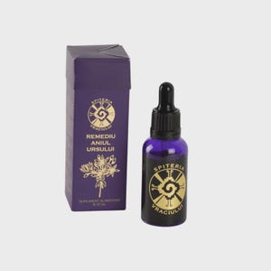 Op de afbeelding: Een paarse doos en een donkerblauwe glazen fles met een zwarte druppelaar. De doos en de fles hebben gouden tekst en een spiraalvormig ontwerp. Op de doos staat "SPITERIA VRACIULUI REMEDIU ANIUL URSULUI". De fles bevat een donkerblauwe vloeistof.