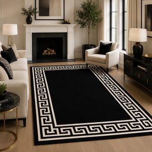 Pode incluir: Um tapete retangular com um campo central preto sólido rodeado por uma borda larga de cor creme decorada com um padrão geométrico grego repetitivo. O tapete está posicionado sobre um piso de madeira clara em uma sala de estar.