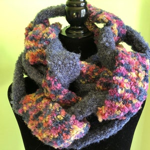 May include: A blue and multi-colored knitted infinity scarf with a fuzzy texture.