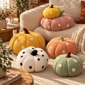 Peut inclure: Une collection de six coussins en forme de citrouille en tissu texturé. Les coussins présentent diverses couleurs, notamment jaune, rose, orange, blanc et vert, chacun décoré de pois contrastants et d'une petite tige sur le dessus.
