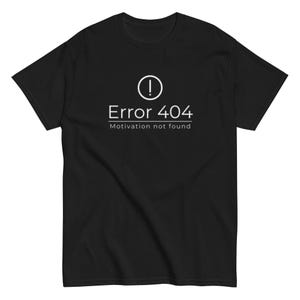 Könnte beinhalten: Ein schwarzes Kurzarm-T-Shirt mit einem weißen Grafikdruck auf der Brust. Das Design zeigt ein Ausrufezeichen in einem Kreis über dem Text "Error 404" und dem Satz "Motivation not found", der von einer dünnen weißen Linie unterstrichen wird.