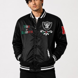 May include: A black satin varsity jacket featuring a white and black striped collar, cuffs, and hem. The chest displays the Raiders logo, floral embroidery, and the text Viva los Raiders in green and red. A red letter A is on the sleeve.