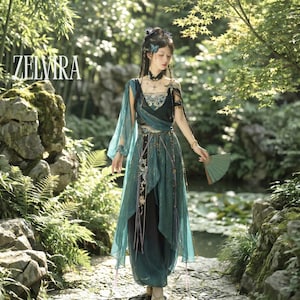May include: A teal and black fantasy-style dress with sheer sleeves and intricate embroidery. The dress features a layered skirt and is accessorized with a fan and delicate jewellery. The word "ZELVIRA" is displayed in white text.