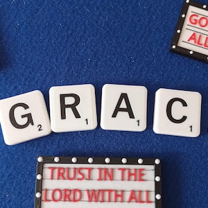 Puede incluir: Azulejos blancos deletrean "GRACE" sobre una superficie azul, con letreros adicionales que dicen "WALK BY FAITH", "GOD IS GOOD! ALL THE TIME" y "TRUST IN THE LORD WITH ALL".
