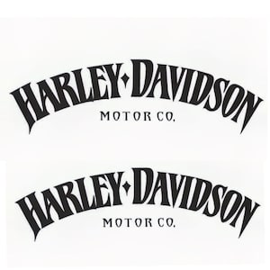 May include: Two black Harley-Davidson Motor Co. decals on a white background. The text is in a stylized, arched font. The decals are identical, with the Harley-Davidson logo and text.