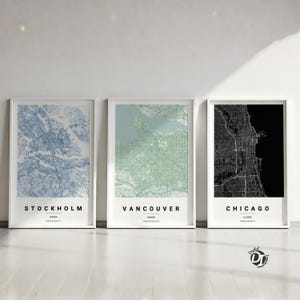 May include: Three framed wall art prints featuring detailed city street maps of Stockholm in blue, Vancouver in green, and Chicago in black. Each print includes the city name, country or state, and coordinates in a clean, modern sans-serif font.