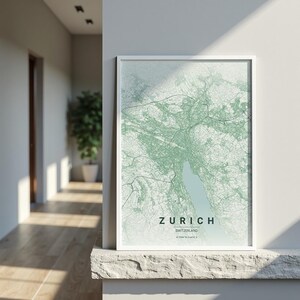 Può includere: Una stampa incorniciata della mappa di Zurigo, Svizzera, nelle tonalità del verde e del bianco. Il nome della città è visualizzato in grassetto, con un carattere sans-serif in basso, con il paese e le coordinate sottostanti. La mappa è racchiusa in una cornice bianca.
