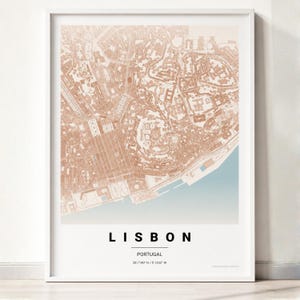 Può includere: Una stampa cartografica incorniciata di Lisbona, Portogallo, con una griglia stradale color rame su sfondo chiaro. La parte inferiore riporta il testo LISBON, PORTUGAL e le coordinate 38.7140 N / 9.1333 W in un carattere nero e pulito.