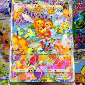 May include: A holographic Combee Pokémon card with a colorful floral background. The card features a large orange and yellow Combee character with the text "Call for Family". The card is encased in a protective sleeve.
