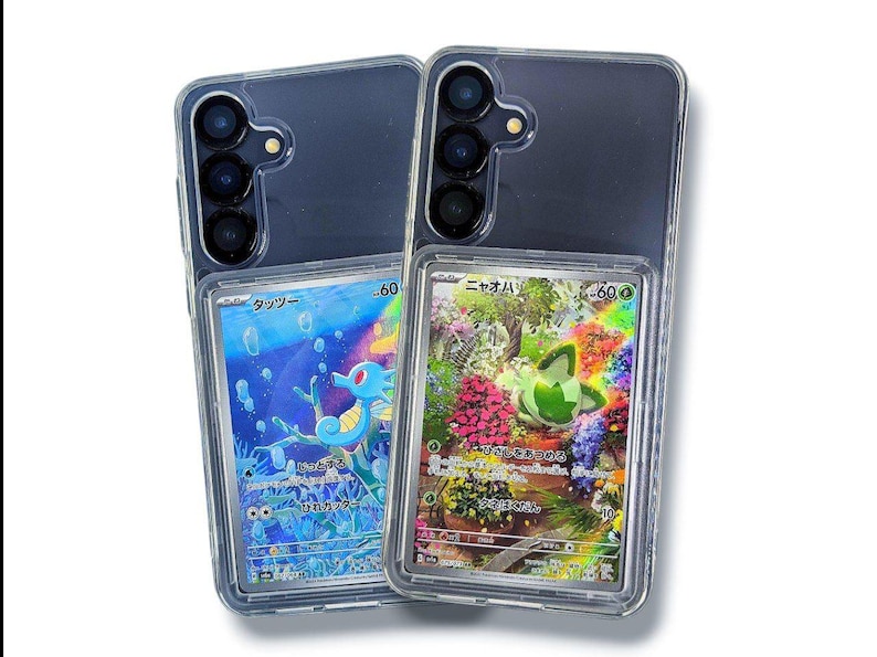 May include: Two clear phone cases with colorful trading cards inside. One card features a blue seahorse in an underwater scene, and the other showcases a green creature in a floral garden. The cases have a dark gray back and a clear frame.