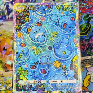 以下が含まれることがあります： ホログラフィックポケモンカード、キャラクターのマリルが特徴です。カードは「Water Gun」と「+20」のテキストが入った青い水色のデザインです。カードは他のポケモンカードに囲まれています。