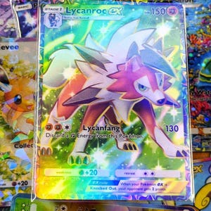 May include: A holographic Lycanroc EX Pokémon trading card. The card features a wolf-like creature with red, white, and purple fur. The card has a HP of 150 and the text "Lycanfang". The card is surrounded by other Pokémon cards.