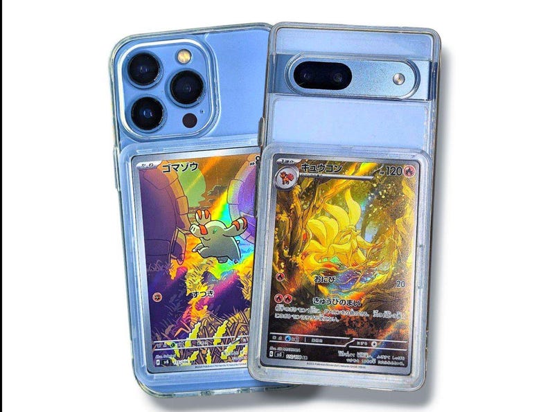 May include: Two clear phone cases with Pokemon trading cards inside. One case holds a blue phone with multiple camera lenses, and the other holds a silver phone. The cards feature colorful illustrations and Japanese text.