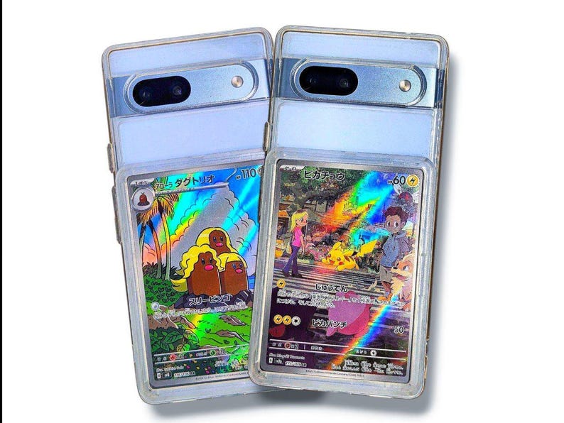 May include: Two clear phone cases with a light blue frame, each holding a Pok&eacute;mon trading card. One card features a Diglett family, and the other showcases Pikachu with other characters. Both cards have Japanese text and holographic effects.