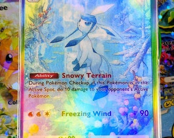 May include: A holographic Glaceon EX Pokémon trading card. The card features a blue and white Glaceon character with the text "Glaceon EX" and "Freezing Wind". The card has a rainbow holographic effect and is encased in a protective sleeve.