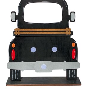 May include: Black wooden cutout of a vintage pickup truck with a wooden bed and a gray bumper. The truck has a cutout for a photo or picture.
