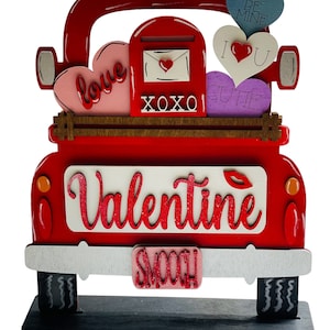 May include: Red wooden truck with a white sign that says "Valentine" and a pink license plate that says "Smooch". The truck is decorated with hearts and the words "love", "XOXO", "cutie", "I love you", and "Be Mine".