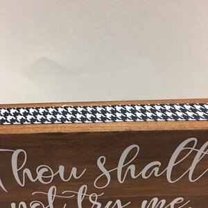 May include: Wooden block with the phrase "Thou shalt not try me" in white script. A black and white houndstooth ribbon trims the top edge. The text "MOM 24:7" is below the main text.