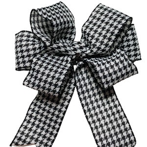 May include: A black and white houndstooth bow with a wired edge. The bow is made of a soft, textured fabric and is perfect for adding a touch of elegance to any occasion.