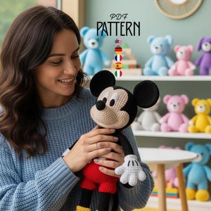 May include: A woman holding a handmade Mickey Mouse plush toy. The toy is black, red, and beige. The background includes a shelf with various colorful crochet teddy bears and the text "PDF PATTERN".