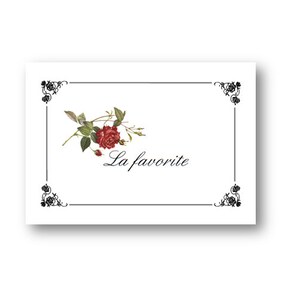 May include: A white card with a black border and a decorative floral design in the top center. The text "La favorite" is written in black cursive script below the floral design.