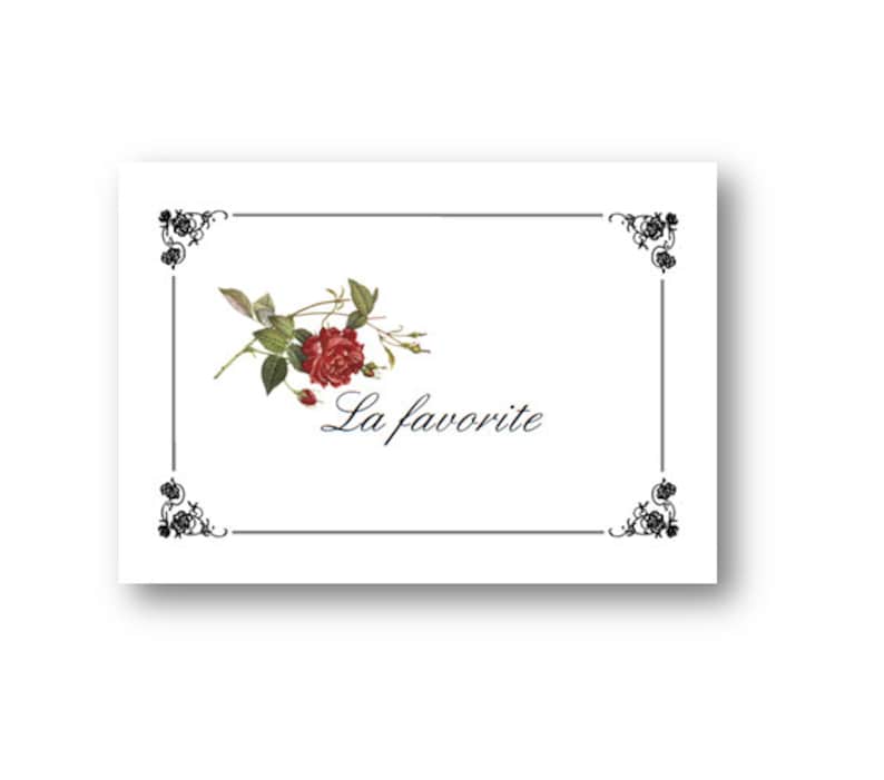 May include: A white card with a black border and a decorative floral design in the top center. The text "La favorite" is written in black cursive script below the floral design.