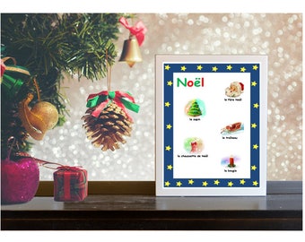 May include: A white framed poster with a blue background and yellow stars around the border. The poster says "Noël" in green letters and has illustrations of Christmas items with French labels, including "le père noël", "le sapin", "le traîneau", "la chaussette de noël", and "la bougie".