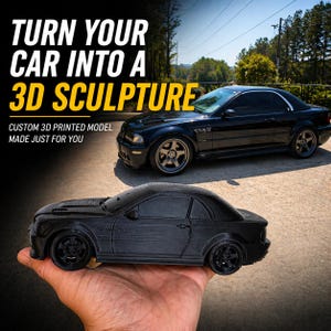 Può includere: Un modello di auto nero stampato in 3D è tenuto in mano, con un'auto nera a grandezza naturale sullo sfondo. Il testo "TURN YOUR CAR INTO A 3D SCULPTURE" è in alto, con "CUSTOM 3D PRINTED MODEL MADE JUST FOR YOU" sotto.
