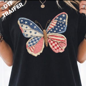 May include: A black t-shirt featuring a large butterfly graphic composed of various fabric patterns including American flag stars and stripes, blue and white gingham, and red and white plaid. The text DTF TRASFER is visible in the upper left corner.