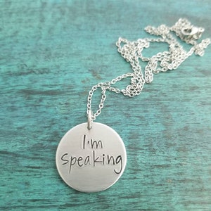 Pu&ograve; includere: Una collana d'argento con un ciondolo rotondo che dice "Sto parlando".