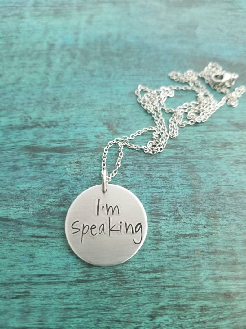 Pu&ograve; includere: Una collana d'argento con un ciondolo rotondo che dice "Sto parlando".