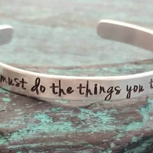 May include: A silver bracelet with the inscription "You must do the things you think you cannot do."