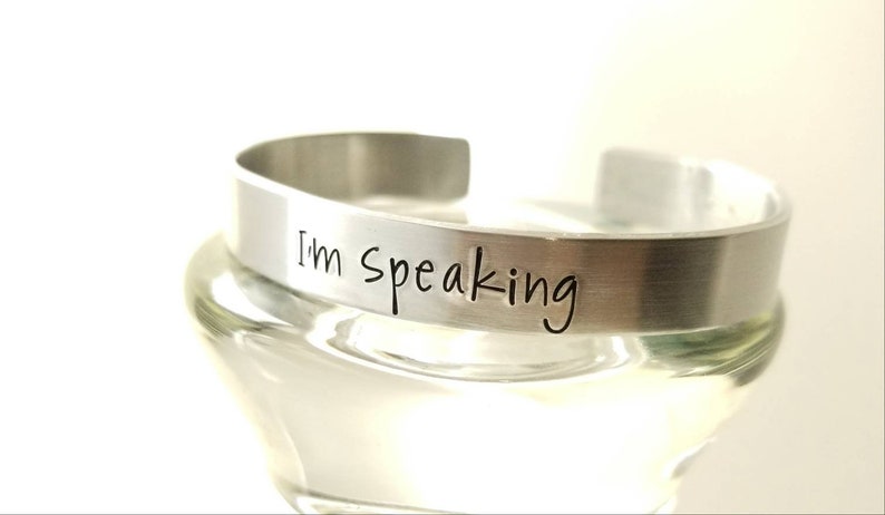 Pu&ograve; includere: Un braccialetto in metallo argentato con le parole "I'm Speaking" incise.