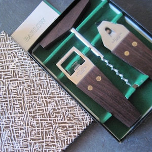 May include: A vintage Barlow bar tool set in a presentation box. The set includes a bottle opener, corkscrew, and other tools with dark wood handles and stainless steel accents. The box has a patterned lid and green velvet lining.