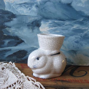 May include: A white ceramic mug with a black handle and the text "But First, Coffee" in a handwritten style. The mug is on a white surface. The mug is 4 inches tall.