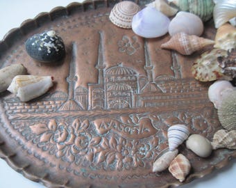May include: A copper tray with an intricate design of a mosque and the word "Ayasofya" inscribed on it. The tray is filled with various seashells in shades of white, brown, and pink.