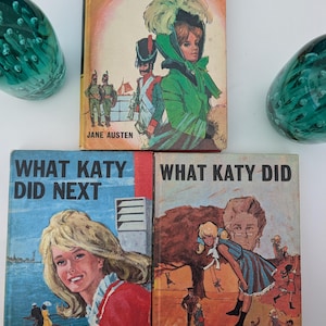 May include: Three vintage hardcover books featuring illustrated dust jackets. The top book is Pride and Prejudice by Jane Austen. The bottom two books are What Katy Did Next and What Katy Did by Susan Coolidge, each displaying colorful character art.