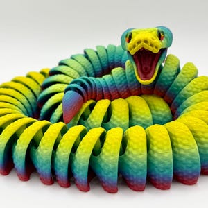 May include: A brightly coloured, articulated snake toy in a coiled position. The snake has a gradient of colours, including yellow, green, blue, and red. The snake's head is open, revealing a red interior. The toy has a textured surface.