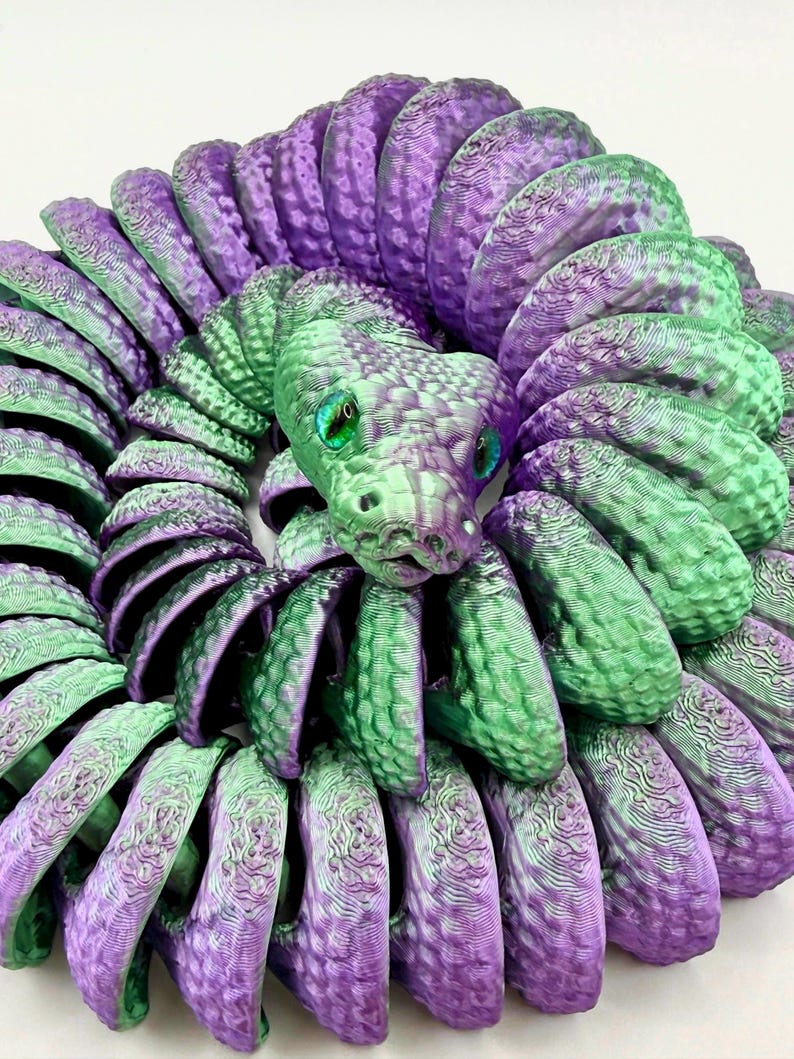 Pode incluir: Escultura de cobra impressa em 3D em tons de roxo e verde. O corpo da cobra &eacute; enrolado, com um padr&atilde;o de escamas detalhado. A cobra tem olhos verdes e uma superf&iacute;cie texturizada, criando uma pe&ccedil;a decorativa &uacute;nica.