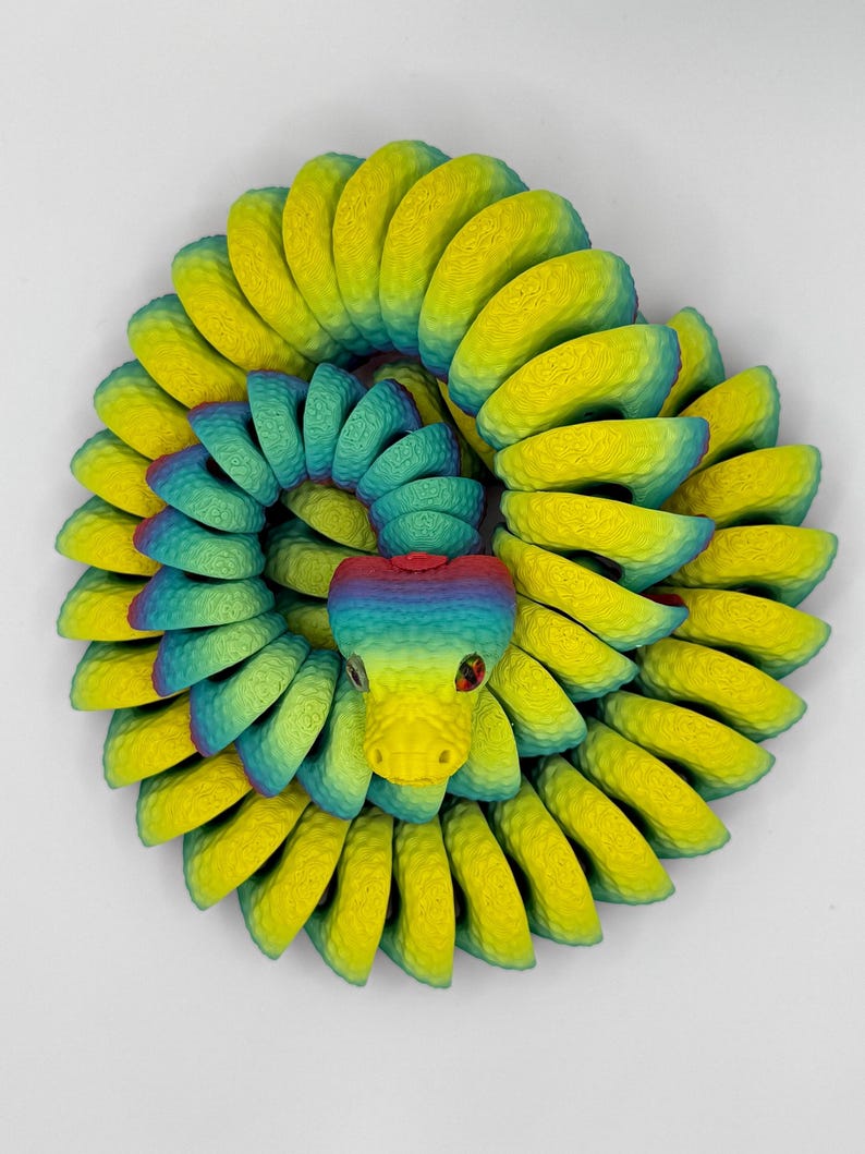 Pode incluir: Escultura de cobra estilizada e colorida, em forma espiral. Apresenta um gradiente de cores amarelo, verde e azul. A cabe&ccedil;a da cobra &eacute; amarela com olhos vermelhos. Uma pe&ccedil;a de arte &uacute;nica.