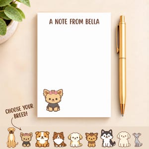 May include: A white rectangular notepad with the text A NOTE FROM BELLA printed at the top and a small cartoon illustration of a Yorkshire Terrier with a pink bow at the bottom left. A gold ballpoint pen is positioned to the right of the notepad.
