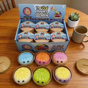 Puede incluir: Una caja expositora de juguetes "The Viral Mystery Dumpling!", cada uno con forma de dumpling colorido con una cara sonriente. La caja contiene varios paquetes individuales de dumpling, con el texto "What Color Will You Get?"