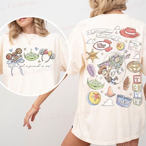 May include: Cream-coloured t-shirt with colourful cartoon graphics from the film Toy Story. The front displays the text "You got a friend in me!" with character illustrations. The back showcases more character art, including Buzz Lightyear and Woody.