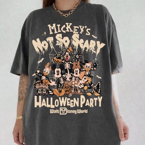 May include: A charcoal grey short-sleeve t-shirt featuring a graphic print with the text Mickey's Not So Scary Halloween Party Walt Disney World. The design displays various cartoon characters in skeleton costumes with pumpkins and bats.