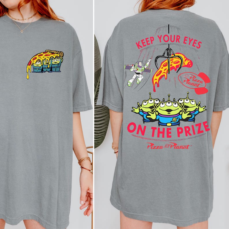 May include: Gray t-shirt featuring a cartoon pizza slice with three green aliens on the front. The back of the shirt has the text "KEEP YOUR EYES ON THE PRIZE" with Pizza Planet graphics and Buzz Lightyear.