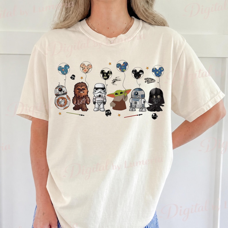 Puede incluir: Camiseta color crema con un dise&ntilde;o tem&aacute;tico de Star Wars. El gr&aacute;fico incluye varios personajes como BB-8, Chewbacca, un Stormtrooper, Yoda, R2-D2 y Darth Vader, cada uno sosteniendo un globo. Los globos tienen orejas de Mickey Mouse.